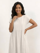 Woman wearing a capped-sleeve voluminous pleated midi dress with pockets and flowing skirt