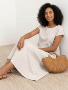 Woman wearing capped-sleeve voluminous pleated midi dress with flowing skirt and pockets