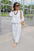 Woman wearing white cotton-linen monochrome relaxed longline top and wide-leg pants set with sunglasses and accessories outdoors