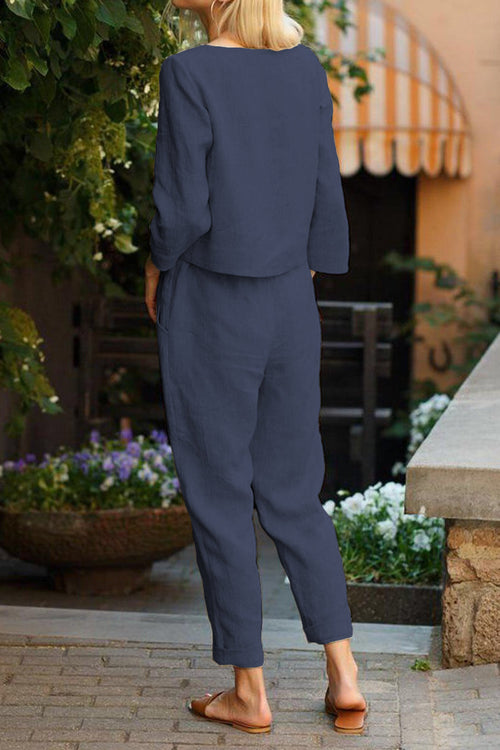 Back view of woman wearing navy cotton-linen monochrome capsule relaxed longline top and fluid wide-leg pants outdoors