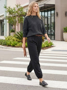 Woman wearing European Minimalism relaxed black sweater top and trouser set walking outdoors