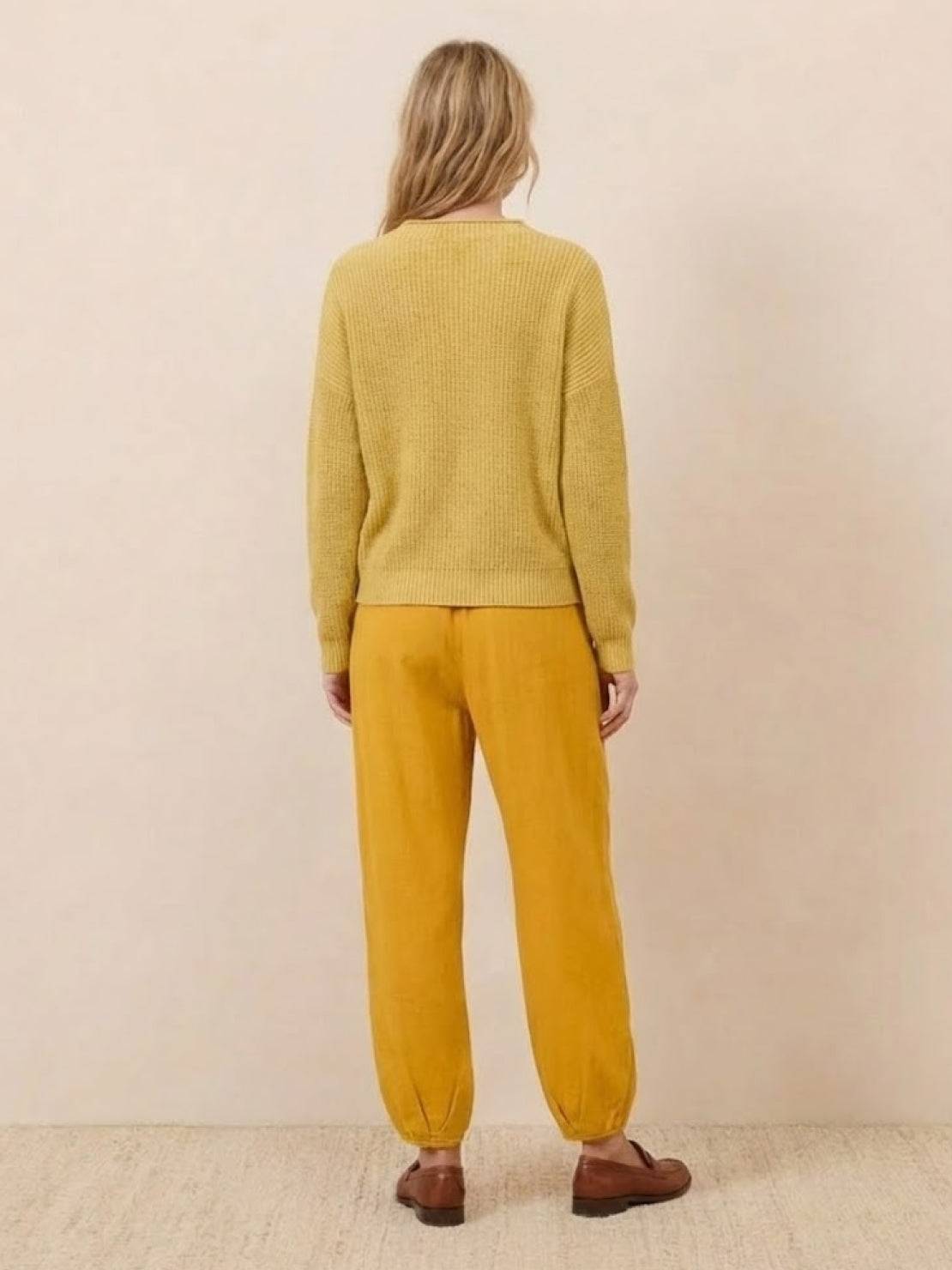 Woman wearing European minimalism relaxed yellow knit sweater and mustard trousers set, back view