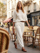woman wearing European minimalism relaxed white sweater top and trouser set walking outdoors at cafe