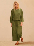 Woman wearing loose solid color olive green two-piece set with long sleeves and wide-leg pants
