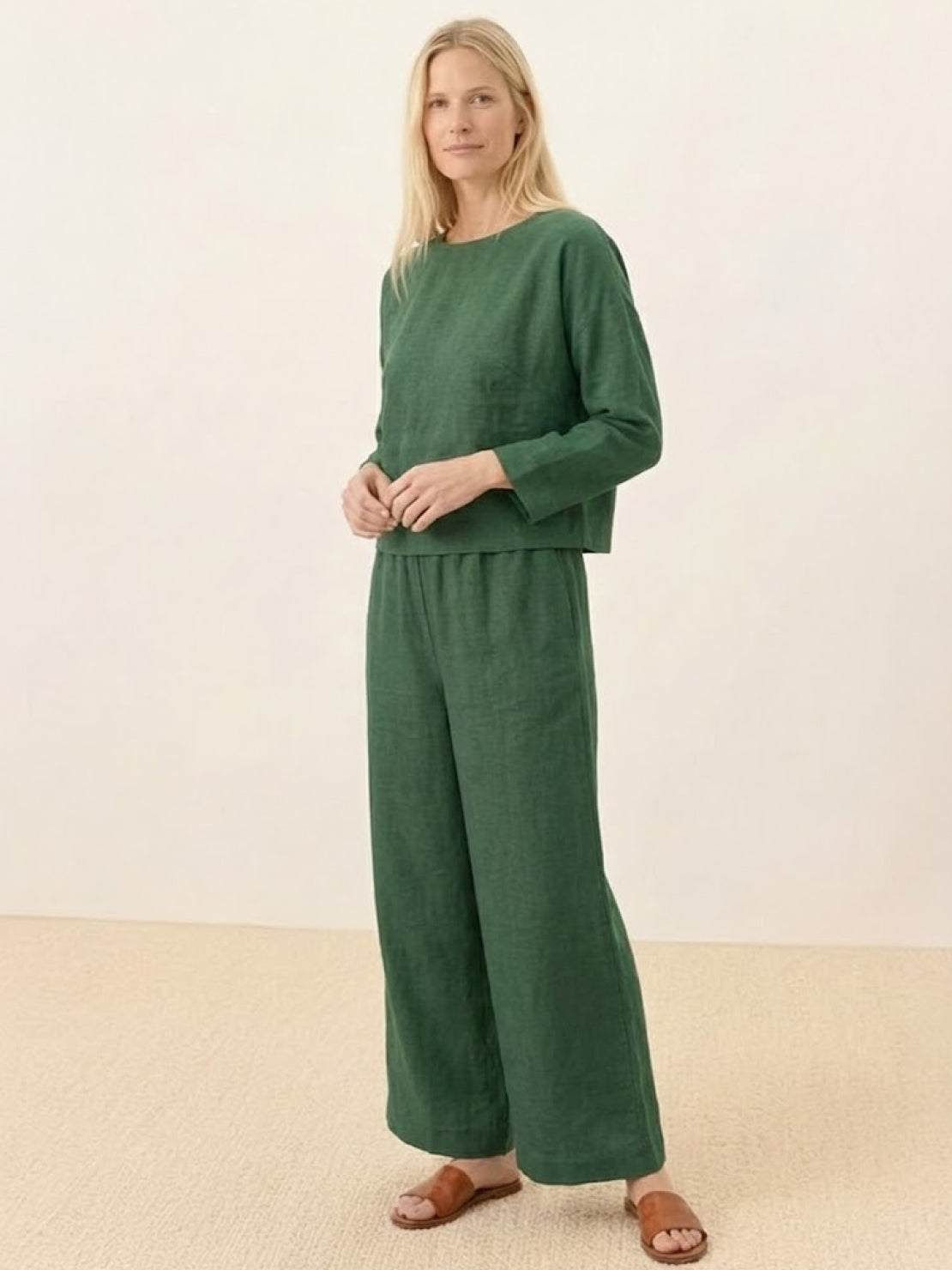 Woman wearing loose solid color two-piece set in green linen-feel fabric with wide-leg pants and round-neck top