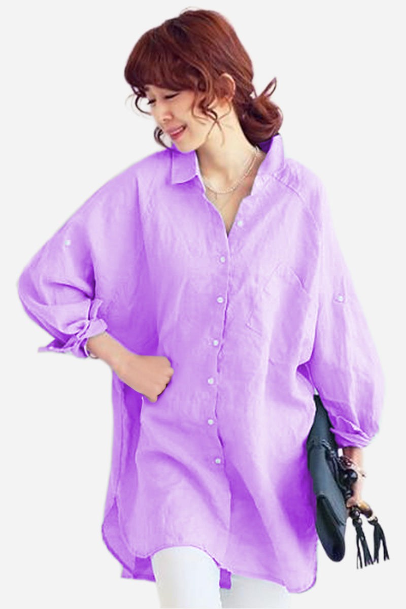 Woman wearing oversized linen shirt in lavender, loose fit with button front and balloon sleeves, styled casually with white pants and black clutch.