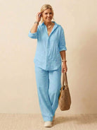 Woman wearing oversized 100% cotton light blue shirt and wide-leg pants co-ord set with a woven bag.