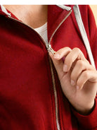 close-up of a hand zipping a red oversized long zip sweatshirt hoodie with gray drawstrings and fleece lining