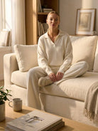 woman in plush and preppy camel two-piece set sitting on beige sofa in cozy living room