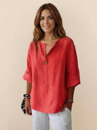 Woman wearing coral pure linen age-defying shirt with button detail and rolled sleeves