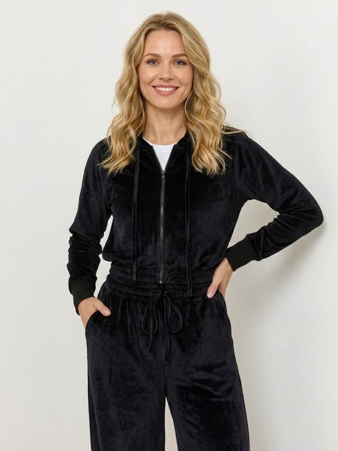 Woman wearing a modern cropped velour hoodie and high-waist velour tracksuit pants in vibrant color