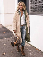 Woman wearing beige sherpa-lined hooded teddy coat with green lining, paired with denim jeans and brown boots, carrying brown handbag walking outdoors