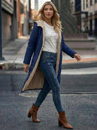 Woman wearing a navy sherpa-lined hooded teddy coat with beige lining, paired with jeans and brown ankle boots, walking on the street.