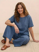 woman wearing blue loose fit co-ord set with wide-leg pants and short-sleeve top sitting on floor