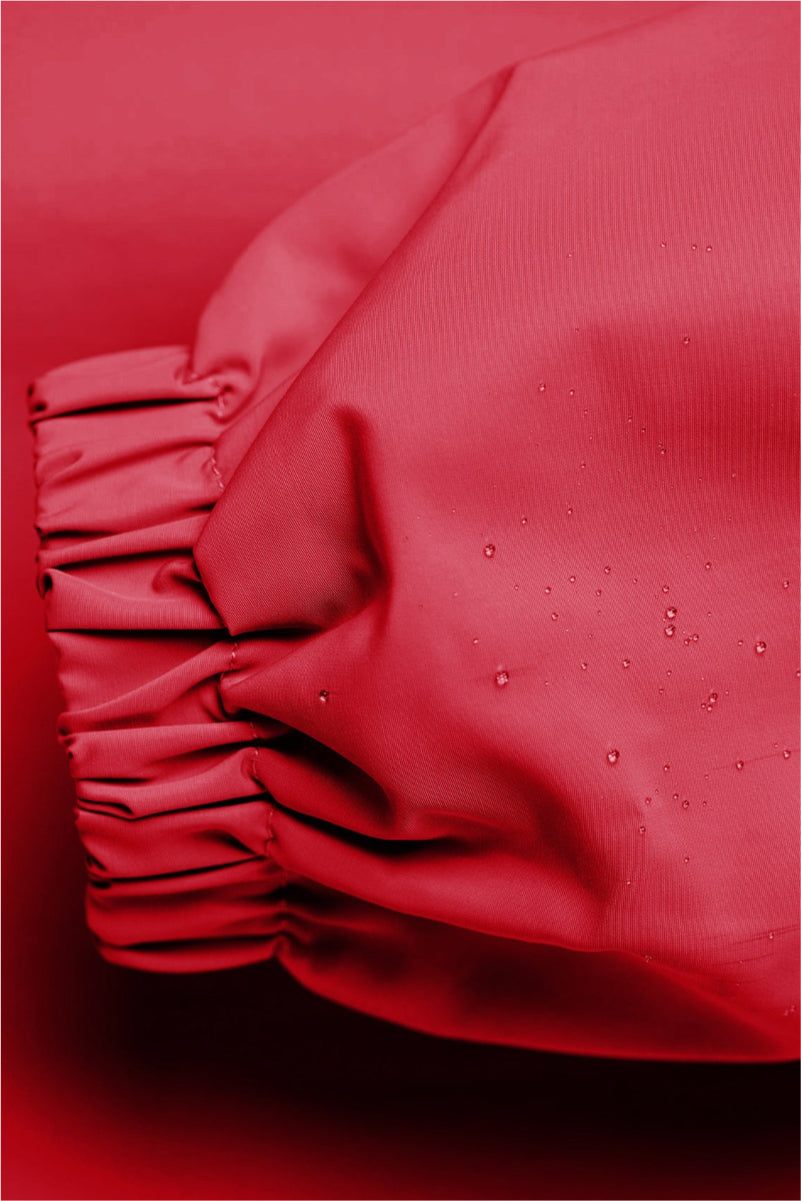 Close-up of red Rain Couture Windbreaker sleeve with water-resistant fabric and elastic cuff detailing.