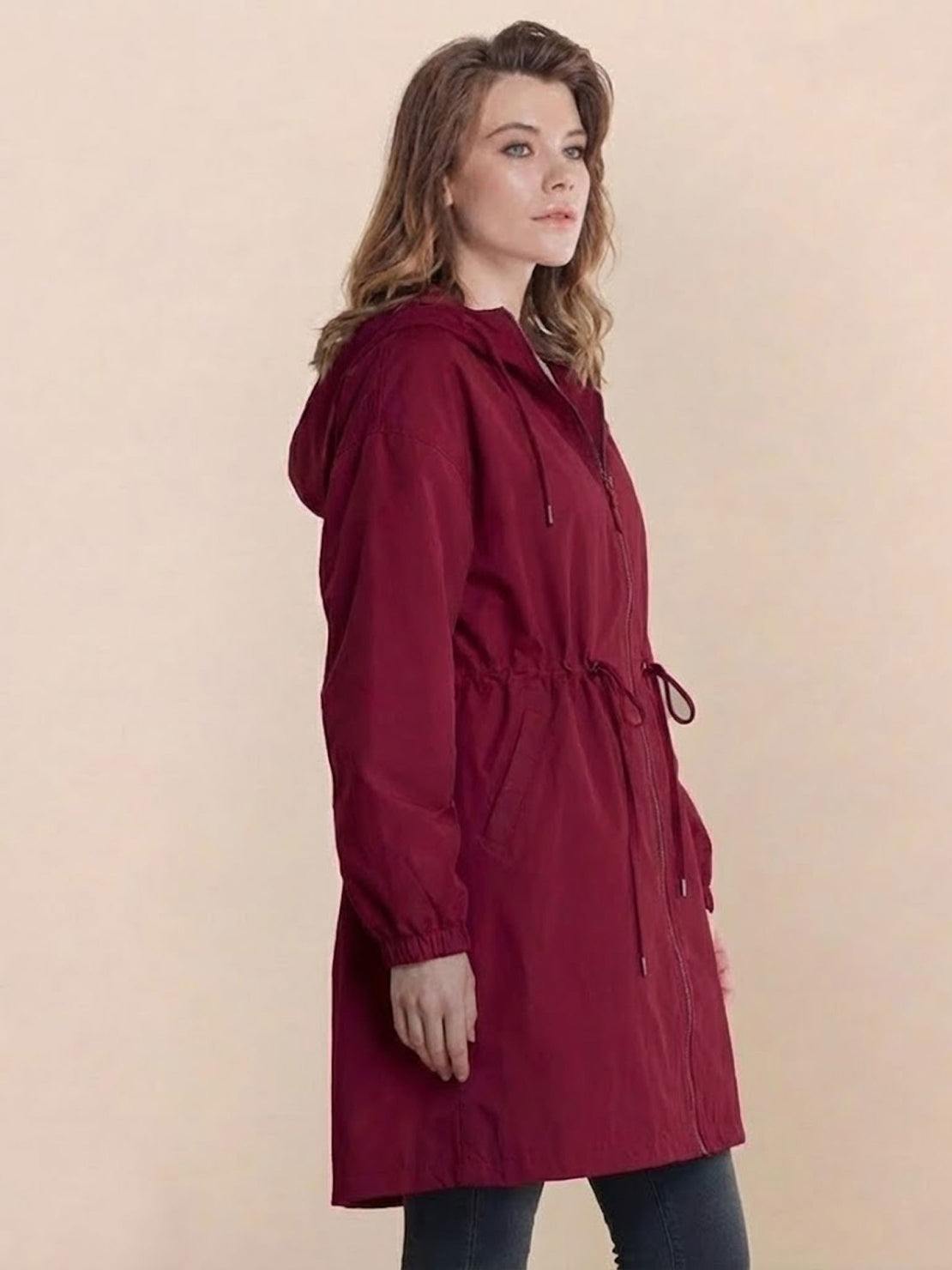Woman wearing burgundy Rain Couture Windbreaker with hood and adjustable waist against neutral background