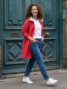 Woman wearing red Rain Couture Windbreaker with white t-shirt and blue jeans walking outdoors